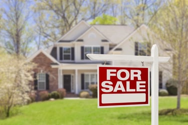 large house and yard with for sale sign in front
