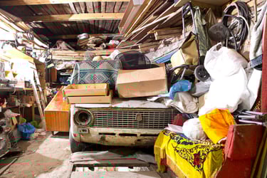 garage cluttered with old junk, cars, tools, boxes