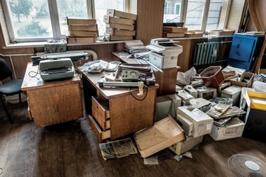 office space with great windows that is overrun with large amounts of clutter and unused supplies