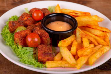 Nuggets de pollo frito crujientes con papas fritas sazonadas, salsa para mojar y tomates cherry fres