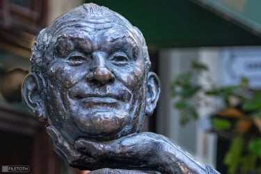 Close-up of a hand holding the head of the Géza Hofi statue, symbolizing humor and reflection.
