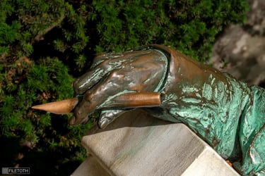 Close-up of Anonymous’s hand holding a quill pen in Miklós Ligeti’s 1903 statue.