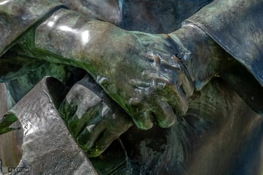 Close-up of Kálmán Latabár's clasped hands holding a crown on the bronze statue.