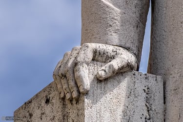 Close-up of Klebelsberg’s right hand resting on a marble block against a cloudy sky.