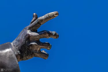 Babits’ hand, finger pointing upwards, bronze texture in natural light.