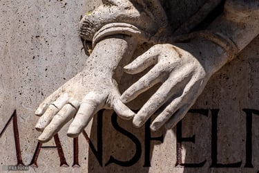 Close-up of Péter Mansfeld's handcuffed hands with outstretched fingers.
