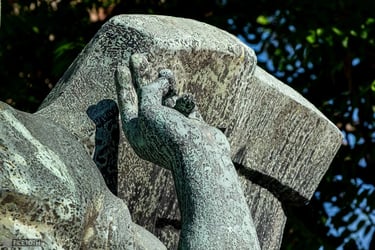 Close-up of angel’s left hand in a unique gesture, wing partially visible.