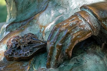 Close-up of Kodály's hand holding a bouquet of wildflowers on the bench.