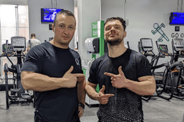 two men standing in a gym with their hands up
