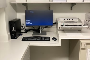 A desktop computer workstation with a Dell PC, monitor, and high-speed document scanner on a white office desk.