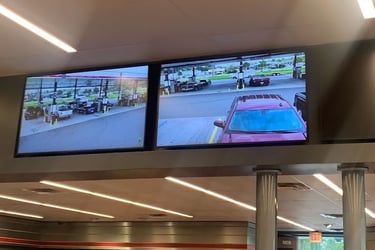 Two security monitors in convenience store showing gas pumps and parking lot 