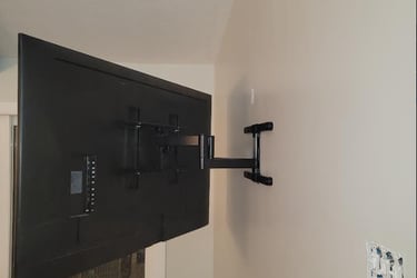 Full motion articulating TV wall mount bracket extending a flat screen television from a wall.