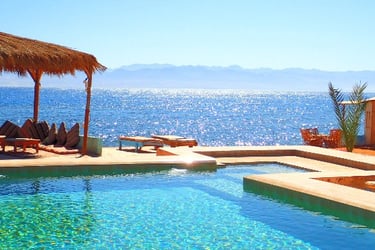 ein Pool mit einem Strohschirm und Stühlen