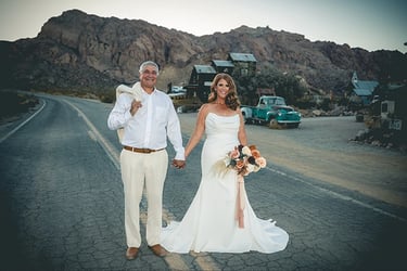 a man and woman holding hands and walking down a road