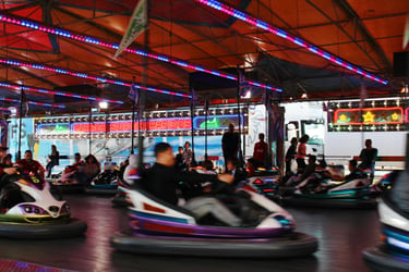 Crowded indoor bumper cars ride at a carnival with colorful neon lights and motion blur.