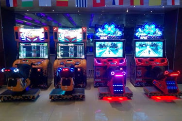 A row of neon lit arcade motorcycle and SnoCross racing games under international flags.