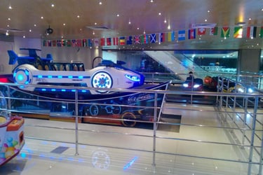A futuristic car-themed amusement park ride with neon blue lights in an indoor family entertainment center.