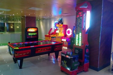 Indoor arcade room with an air hockey table and colorful glowing prize redemption games.