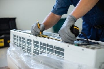 Professional HVAC technician measuring a new air conditioning unit for home installation service.