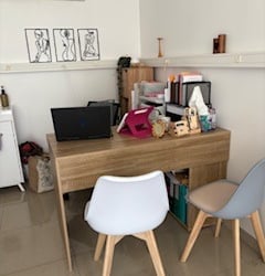 A tidy home office setup featuring a wooden desk, laptop, and two modern chairs.