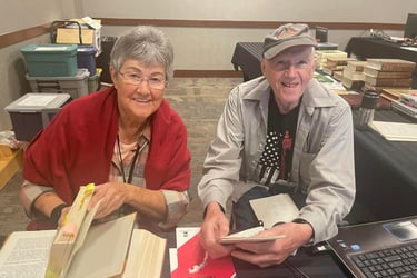 a woman and a man sit at a desk with reference books