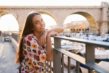 a girl posting for a portrait with vallon des auffes bridge in the background