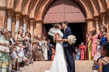 baiser des mariés sur le parvis d’une église, entourés d’une foule joyeuse et célébrante