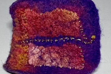 small hand felted brooch in reds and purple