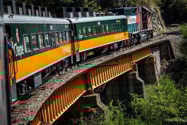 El tren El Chepe cruza un puente amarillo en la Barranca del Cobre, México, mostrando los vagones