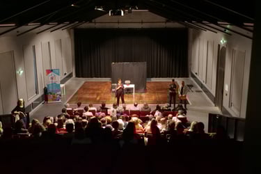 vue arrière large du public avec sur scène 1 femme forum accueil handicapés