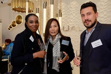 three people standing next to each other holding wine glasses