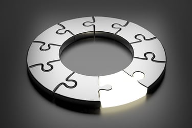 A circular metallic puzzle with one glowing piece representing a complete business solution.