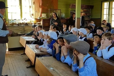Students in historical costumes sitting at vintage wooden desks at the Old Tailem Town School