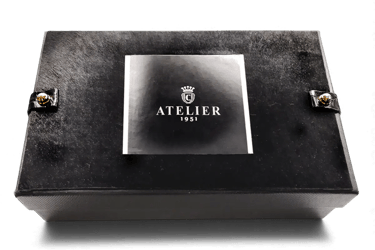 Elegant black Atelier 1951 luxury gift box with silver logo and gold stud accents.