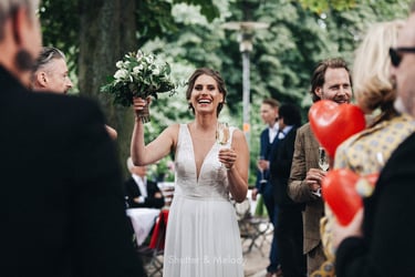 Die Braut lacht und stößt mit ihren Hochzeitsgästen an.