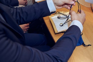 The best man placing wedding bands on necklaces on a plate prior to wedding ceremony.