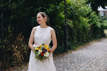 Die Braut hält einen Blumenstrauß und blickt zur Seite.