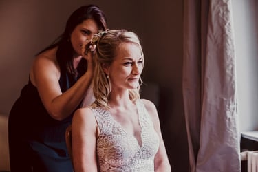 Trauzeugin, die die Haare der Braut richtet.