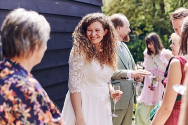 Bride smiling at wedding guest holding a glass of champagne.