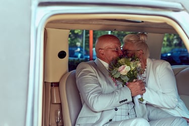 Bride and groom kissing in a car.