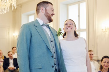 Bride and groom laughing and looking at each other during wedding ceremony.