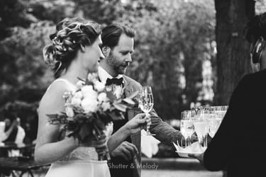 Bride and groom picking up glasses of champagne from a tray.