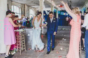 Bride and groom leaving the ceremony having flower petals thrown at them.