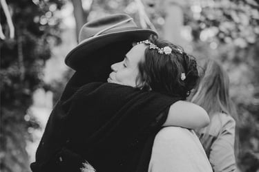 Bride hugging a guest wearing a hat.