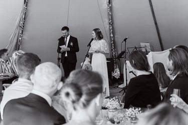 Hochzeitspaar hält Reden in einem Zelt.