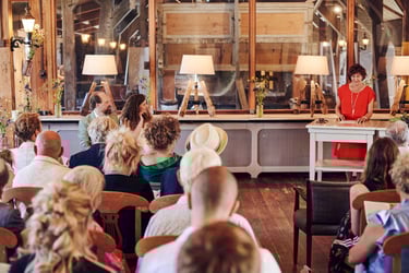 Braut und Bräutigam sehen ihre Mutter in einem roten Kleid an und sprechen.
