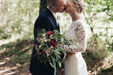 Close-up of the bridal bouquet with the couple kissing in the background.