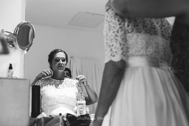 Maid of honor putting on a necklace on the bride in a bathroom.