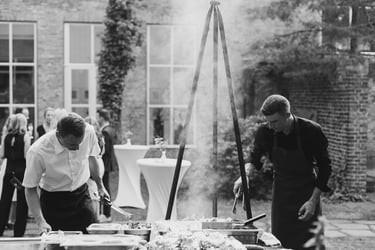 Two cooks grilling food at a wedding reception.