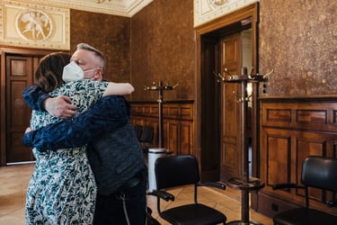 Groom wearing a mask hugging a guest.